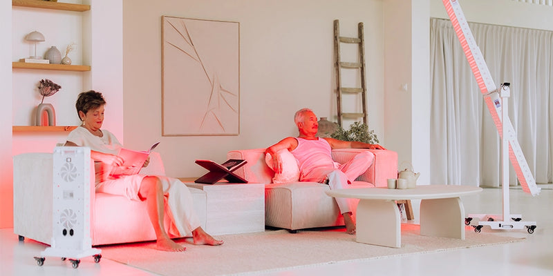 Man en vrouw ontspannen samen op de bank naast een Liroma roodlichttherapie paneel