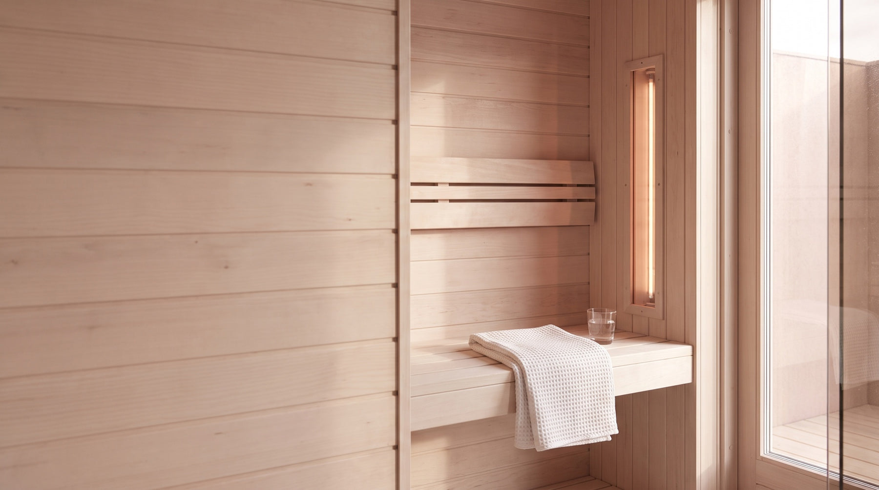 Rustig verlichte infraroodsauna met houten banken, handdoek en een warm gloeiend infraroodelement
